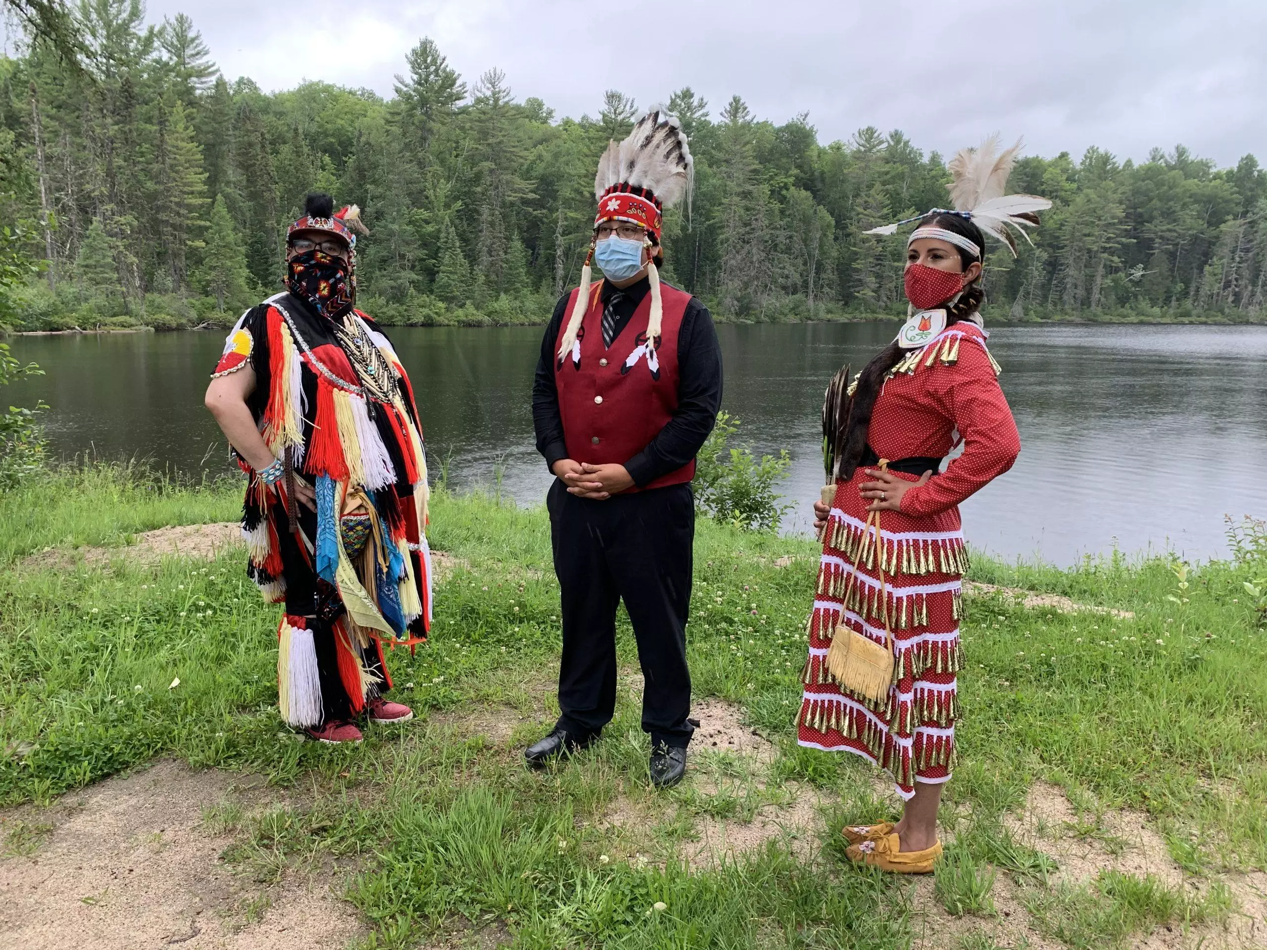 Kitigan Zibi First Nation Chief and other members stand in front of a lake.
